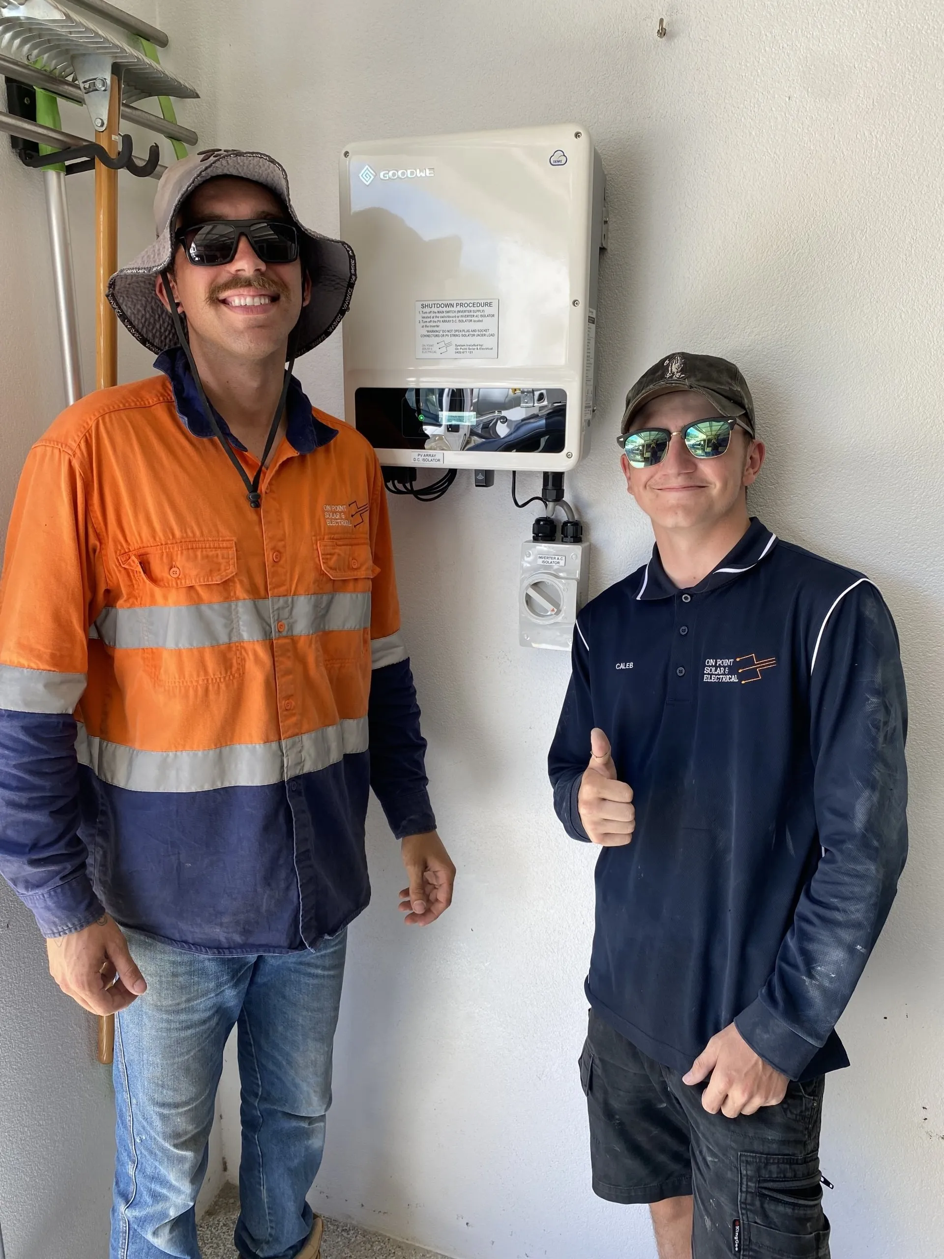 The On Point Solar & Electrical team beside a Goodwe solar inverter they installed in Townsville